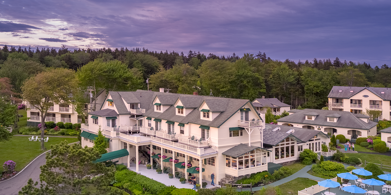 This image features a large estate with a main building surrounded by lush greenery and smaller structures, possibly a resort or hotel.