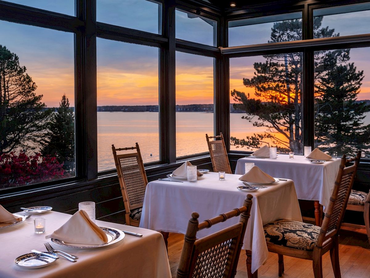 Restaurant with ocean view at sunset, tables set for dining.